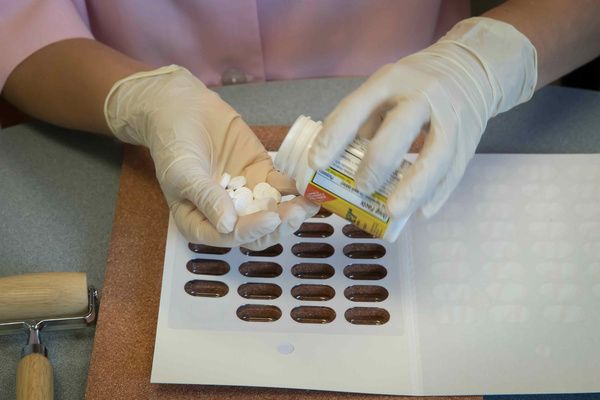 A pharmacist organizes pills using Multi-Dose Packaging Multi-Dose Packaging