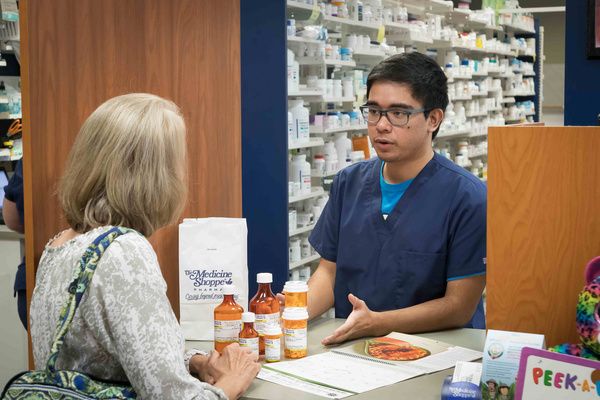 A pharmacist speaks to a patient at the counter Medication therapy management
