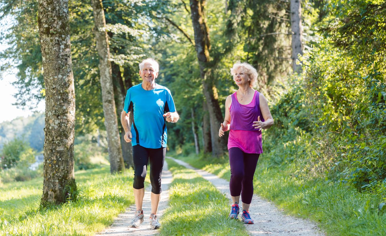 An elderly couple jog on a trail Health and wellness